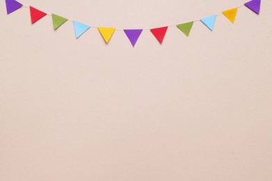 Photo of Colorful bunting flags on beige background, flat lay. Space for text
