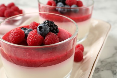 Photo of Delicious panna cotta with fruit coulis and fresh berries served on white marble table, closeup