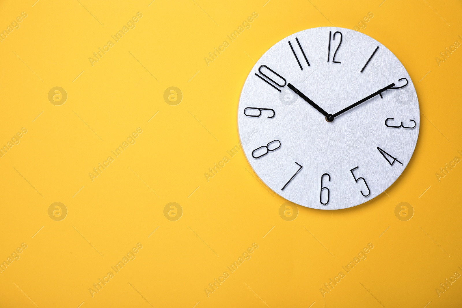 Photo of Modern clock on yellow background, top view. Space for text