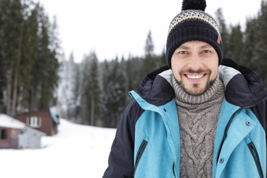 Photo of Happy man in warm clothes outdoors, space for text. Winter vacation