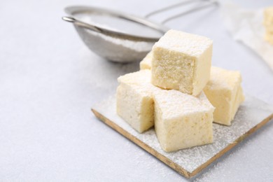 Photo of Delicious sweet marshmallows with powdered sugar on light grey table, closeup. Space for text