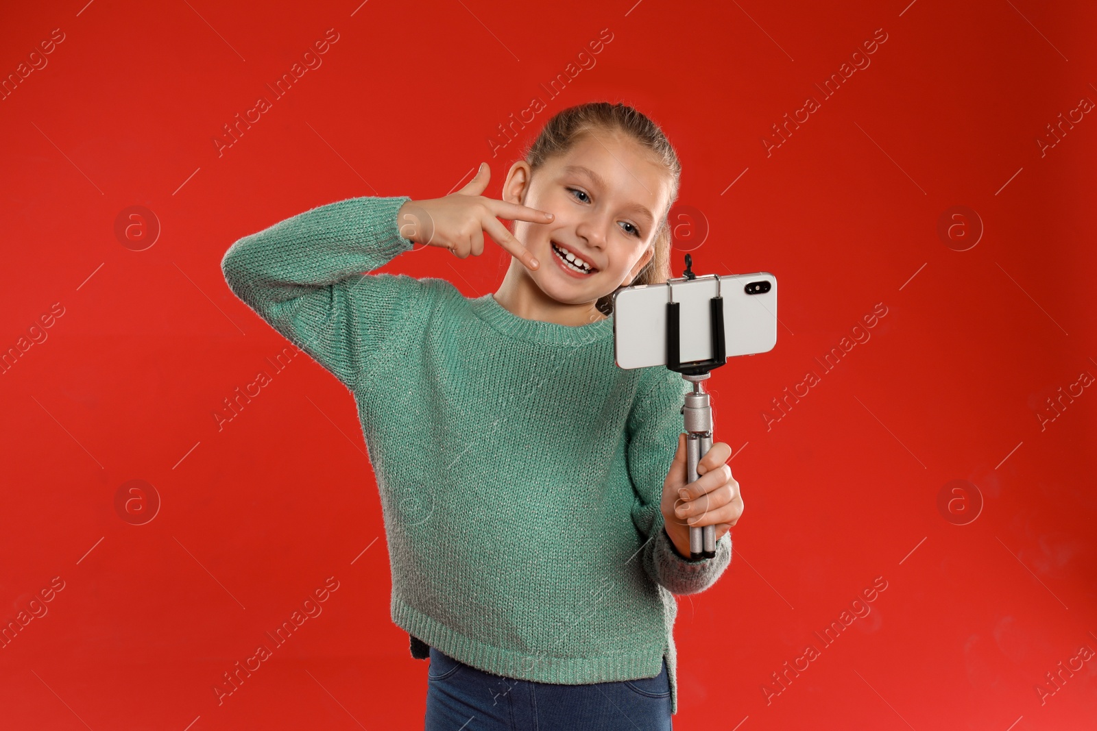 Photo of Cute little blogger recording video on red background