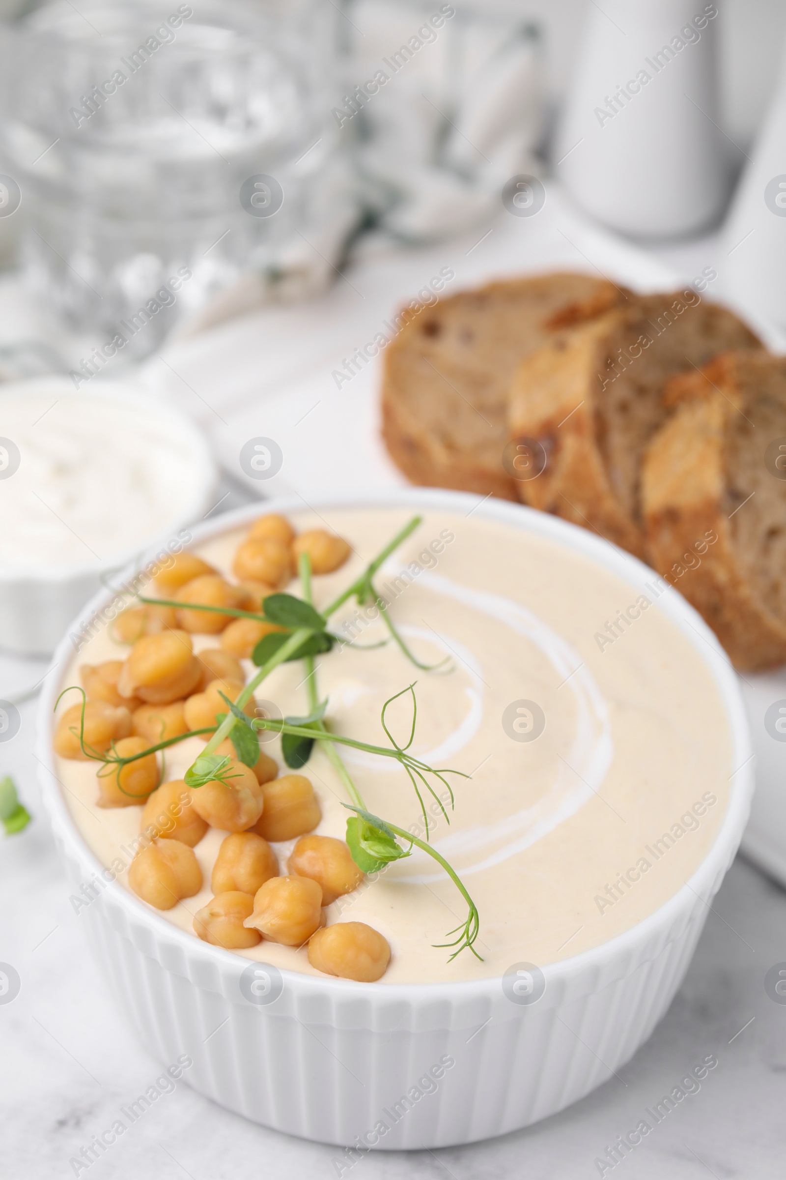 Photo of Tasty chickpea soup in bowl on white marble table