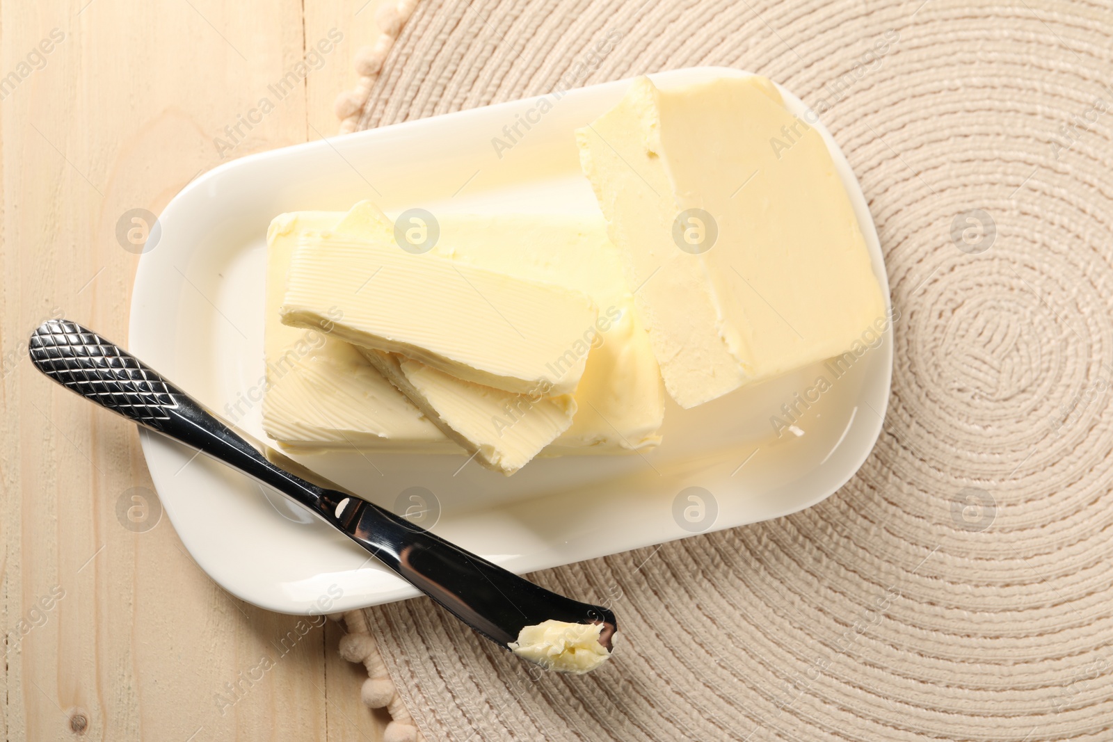 Photo of Tasty butter and knife on wooden table, top view