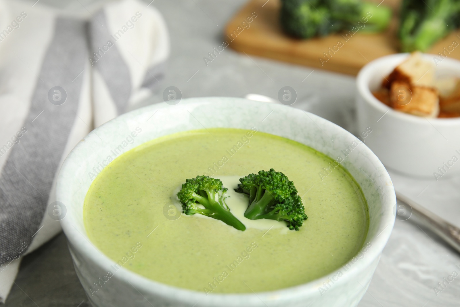 Photo of Bowl of delicious broccoli cream soup on table, closeup