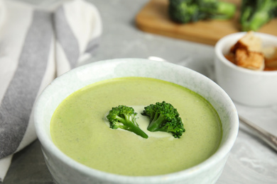 Bowl of delicious broccoli cream soup on table, closeup