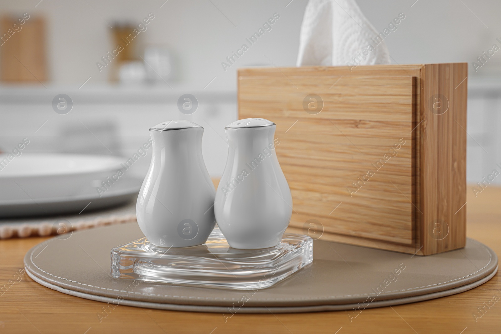 Photo of White ceramic salt and pepper shakers on wooden table