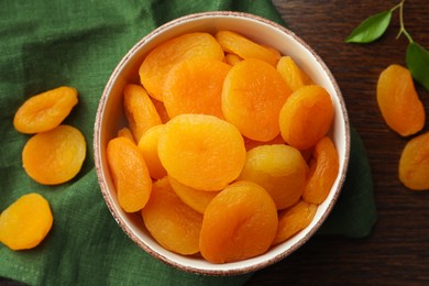 Photo of Bowl of tasty apricots on wooden table, flat lay. Dried fruits