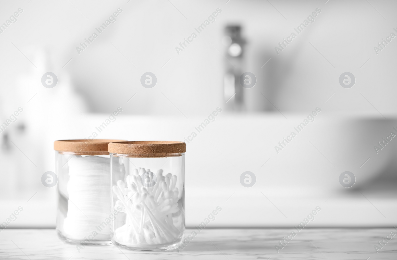 Photo of Glass jars with cotton pads and swabs on white countertop in bathroom. Space for text