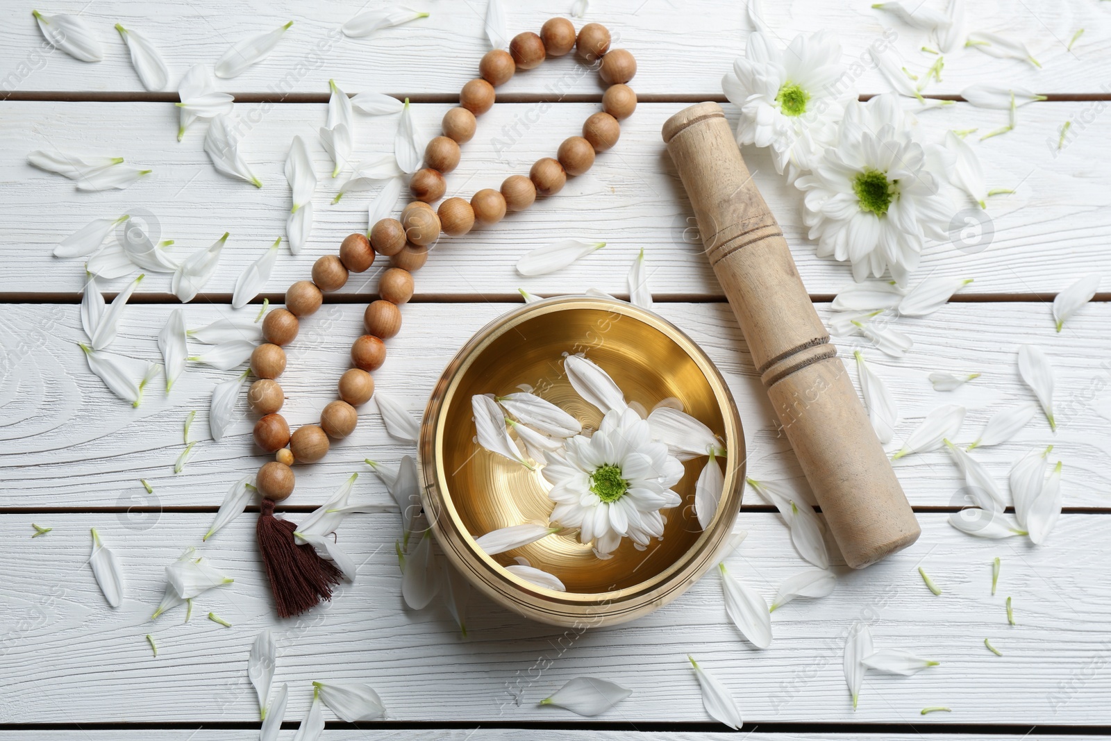 Photo of Flat lay composition with golden singing bowl on white wooden table. Sound healing