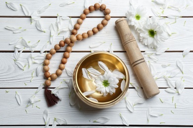 Photo of Flat lay composition with golden singing bowl on white wooden table. Sound healing