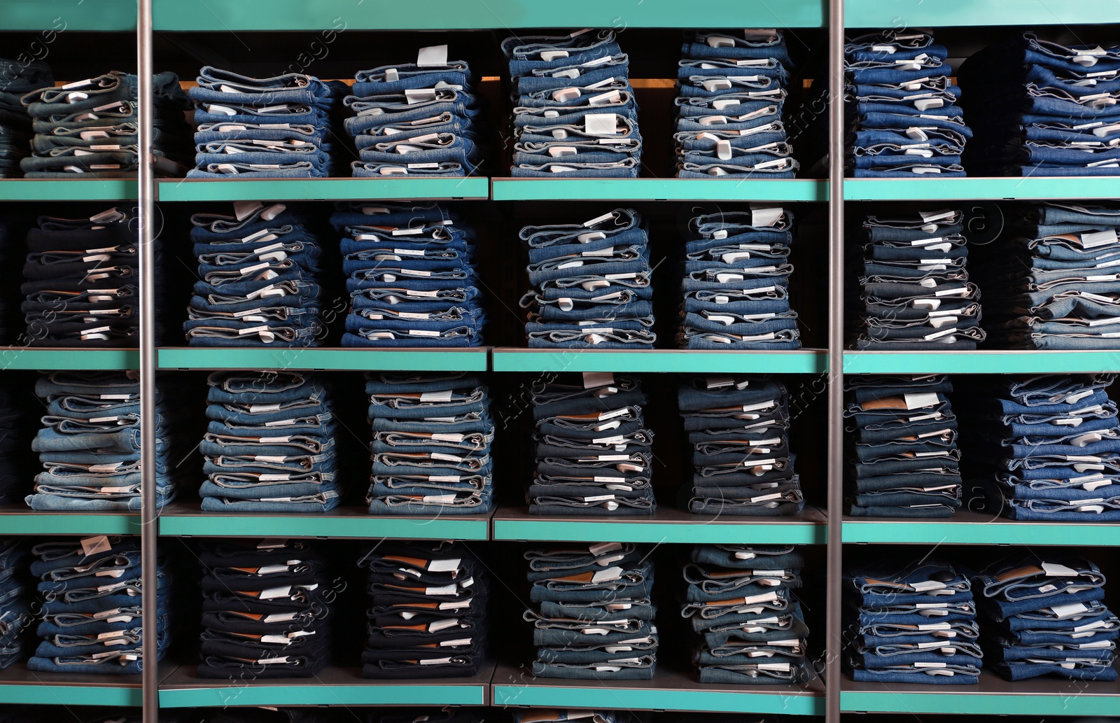 Photo of Collection of stylish jeans on shelves in shop