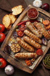 Photo of Tasty grilled sausages and products on wooden table, flat lay