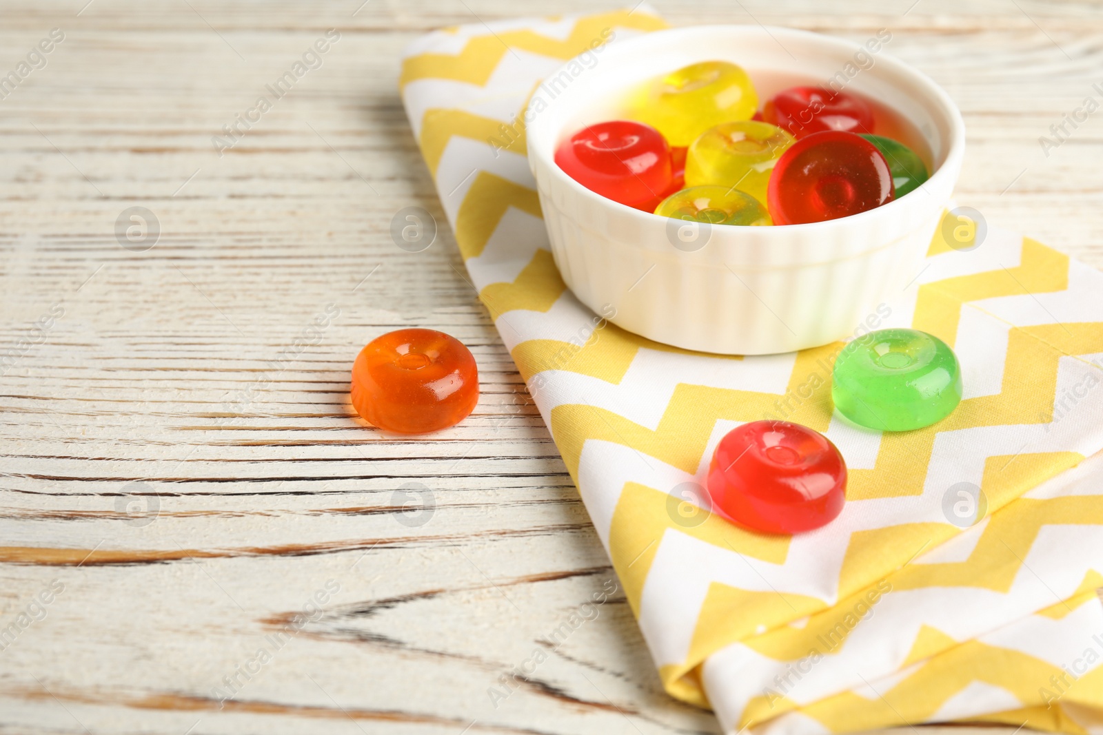 Photo of Bowl with delicious colorful candies on wooden table. Space for text