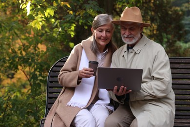 Photo of Affectionate senior couple with laptop spending time together in autumn park