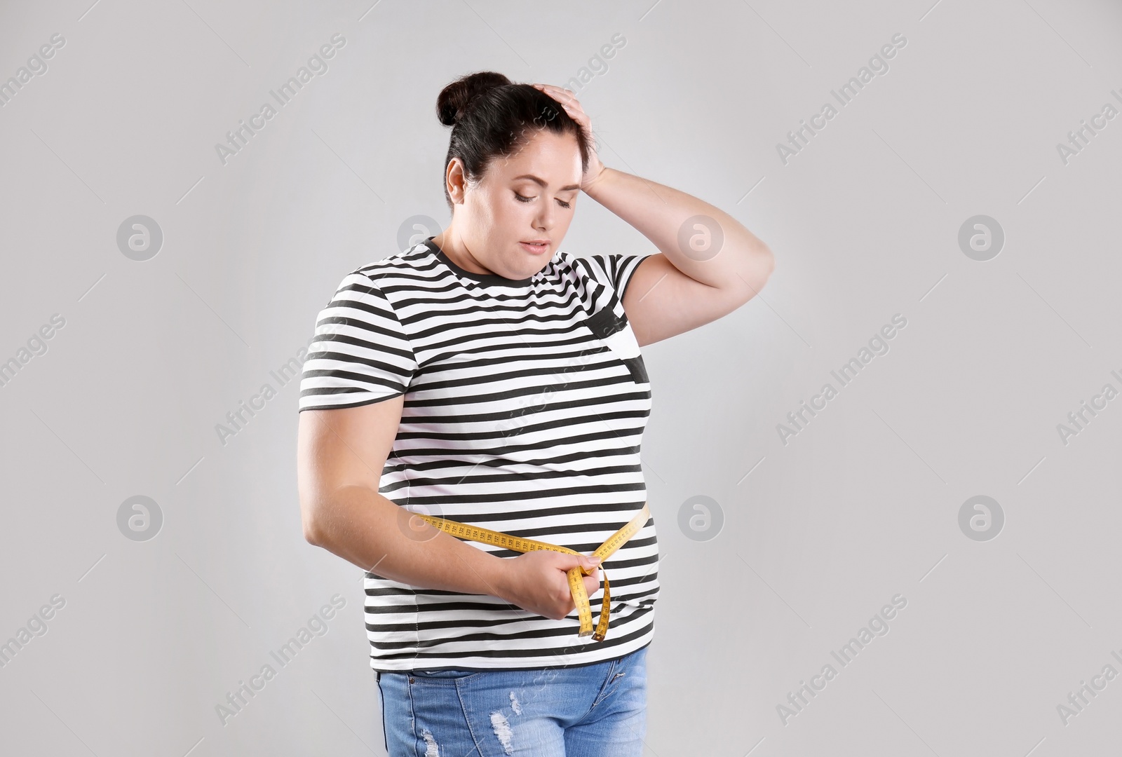 Photo of Fat woman with measuring tape on grey background. Weight loss