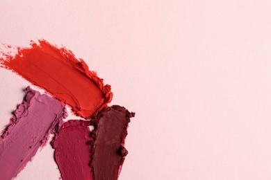 Smears of different bright lipsticks on light background, top view. Space for text
