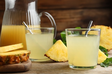 Photo of Delicious pineapple juice and fresh fruit on wooden table