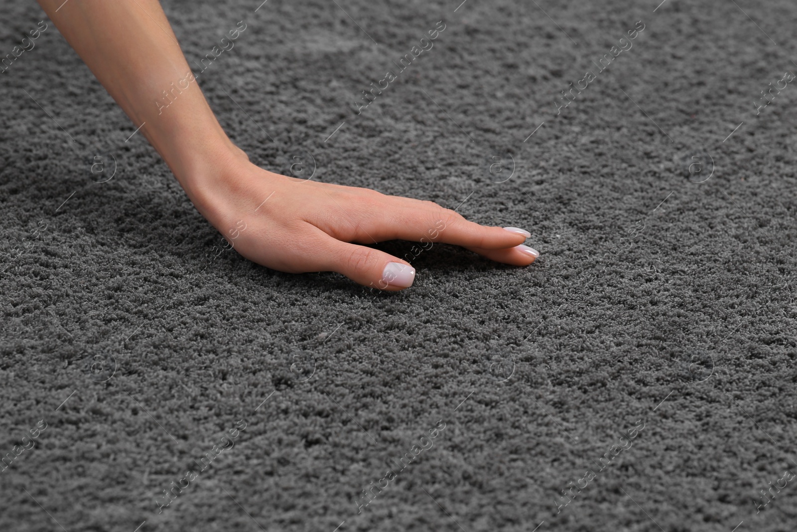 Photo of Woman touching soft grey carpet, closeup view