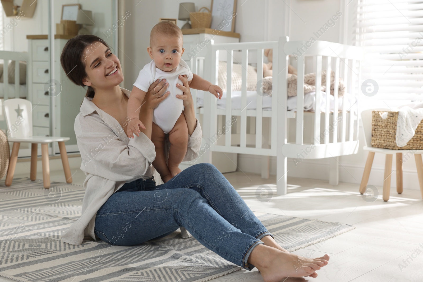 Photo of Happy young mother with her baby in nursery. Space for text