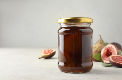 Photo of Jar of tasty sweet fig jam on light table. Space for text