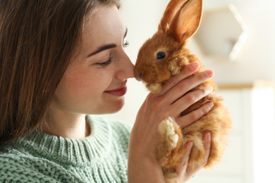 Photo of Young woman with adorable rabbit indoors, closeup. Lovely pet