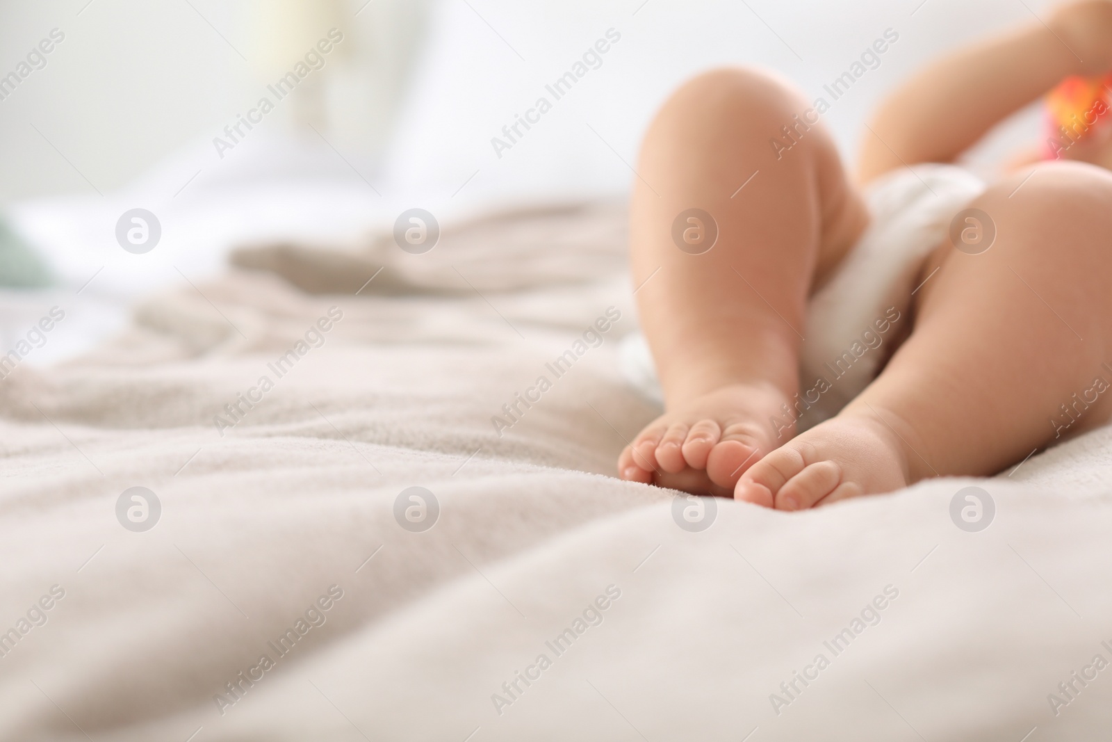 Photo of Cute little baby lying on bed, closeup of legs. Space for text