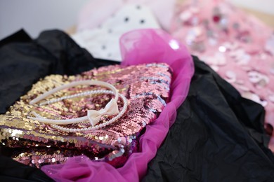 Photo of Headbands and stylish pink carnival costume with sequins in black box, closeup