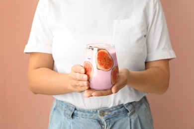 Woman holding fig smoothie on pink background, closeup