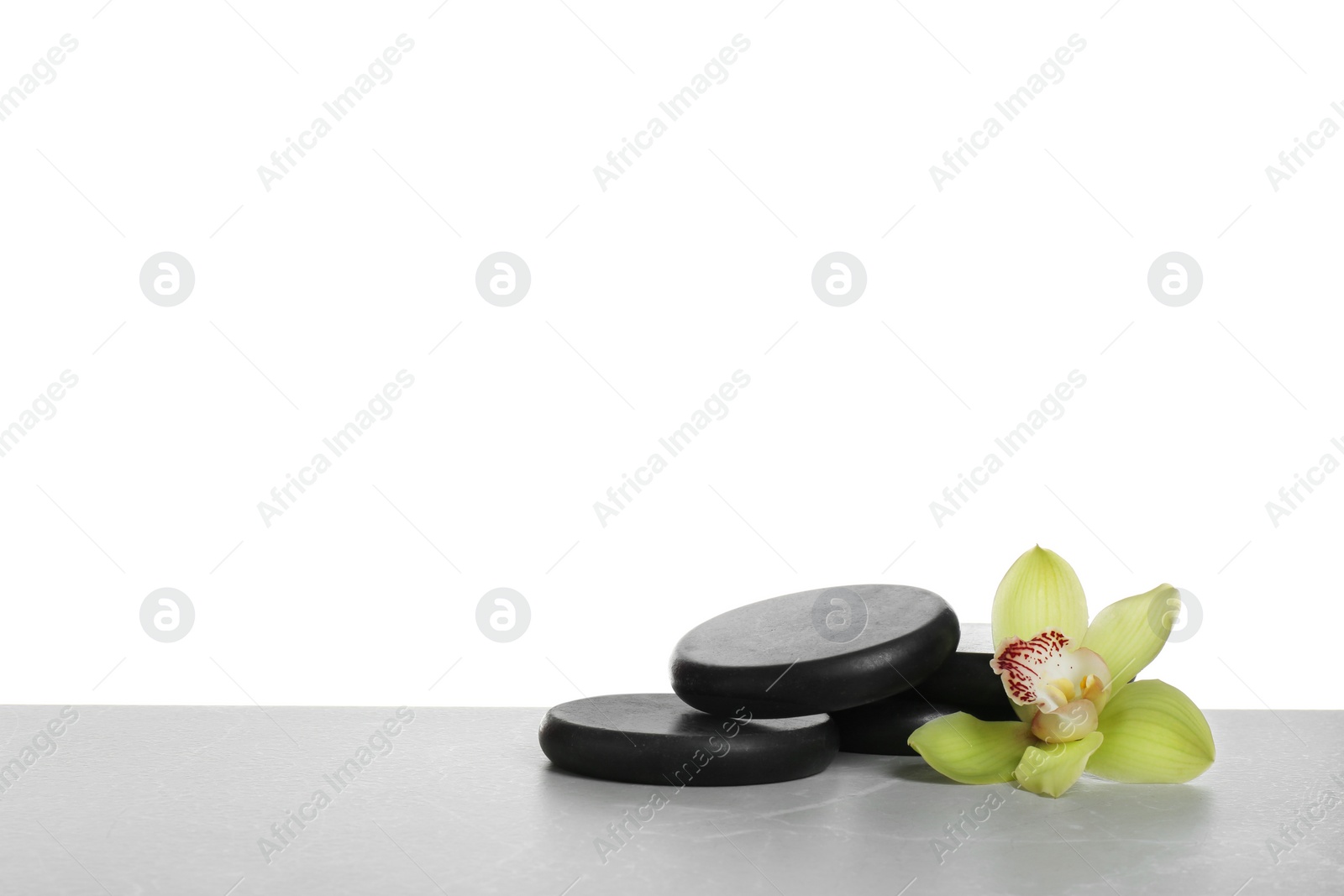 Photo of Black spa stones with orchid flower on white background. Space for text