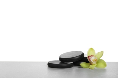 Photo of Black spa stones with orchid flower on white background. Space for text