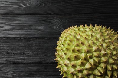 Photo of Ripe durian on black wooden table, top view. Space for text