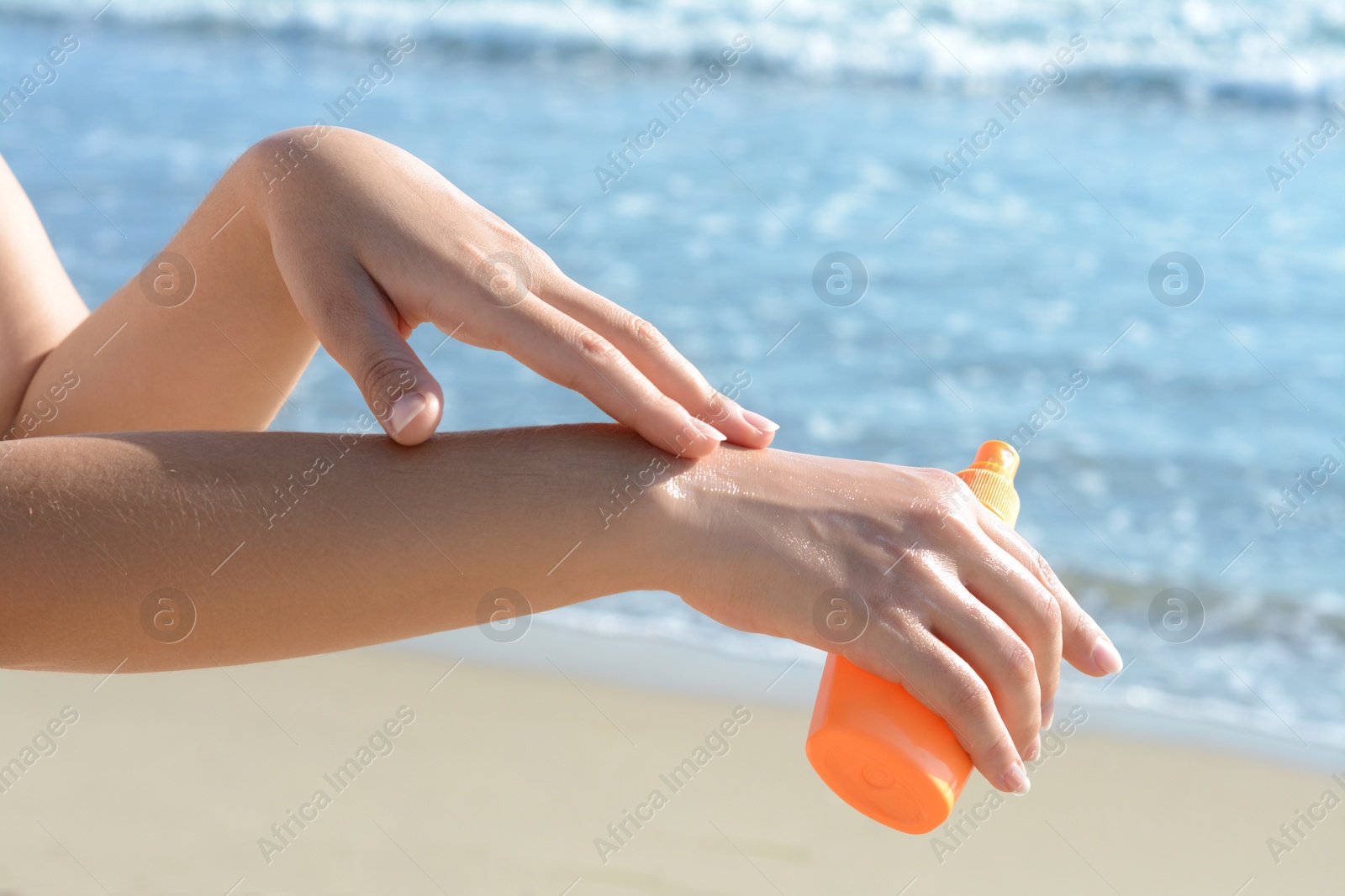 Photo of Woman applying sun protection cream on her hand at beach, closeup