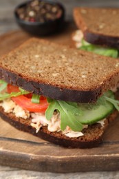 Delicious sandwiches with tuna and vegetables on wooden serving board, closeup