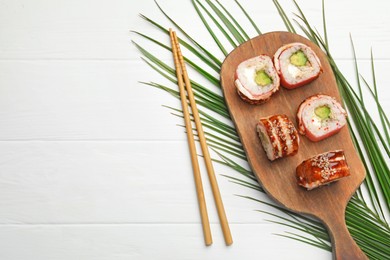 Photo of Delicious sushi rolls and chopsticks on white wooden table, flat lay. Space for text