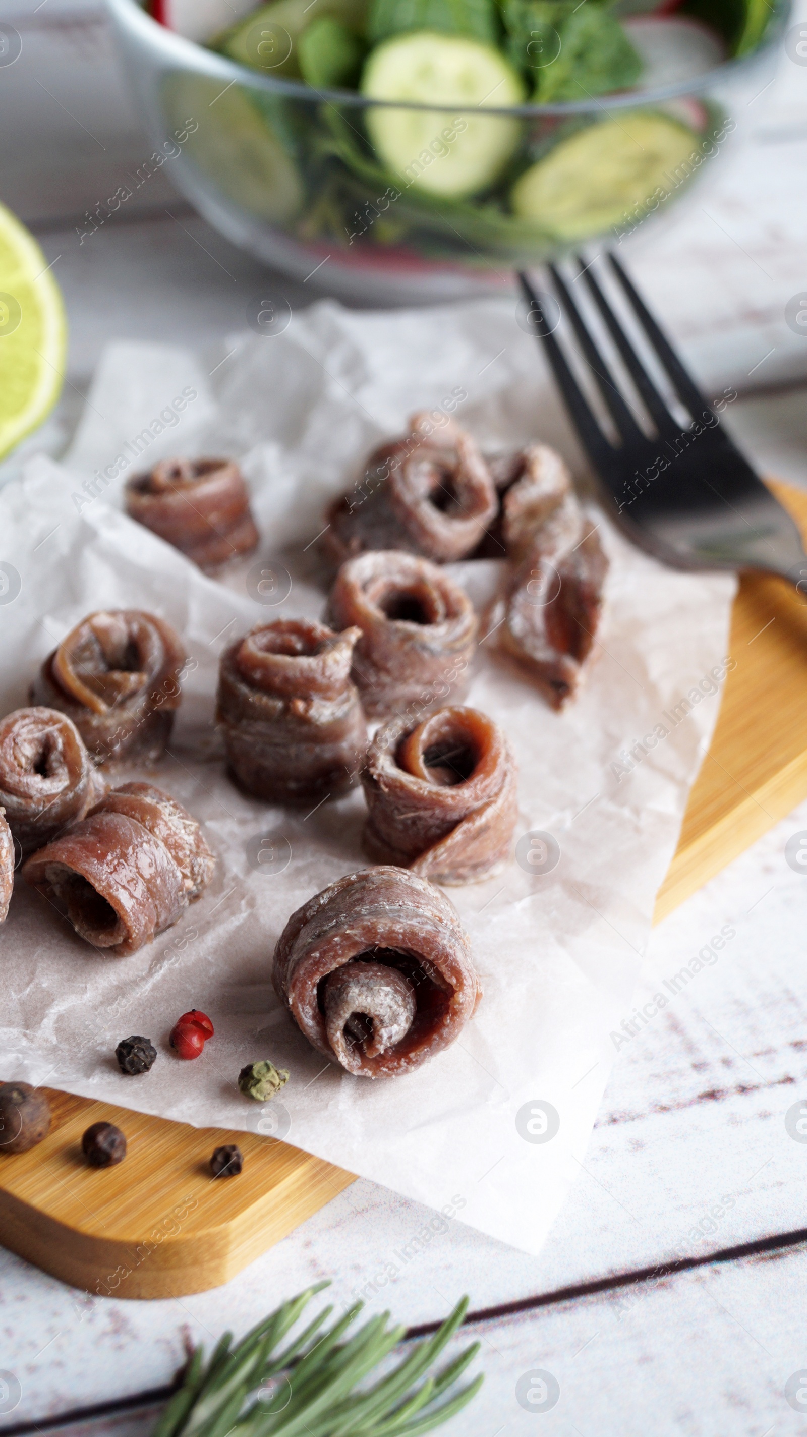 Photo of Canned anchovy fillets, rosemary and lime on white wooden table