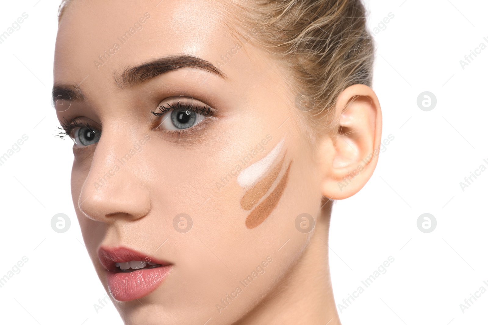 Photo of Young woman with different shades of skin foundation on her face against white background. Professional makeup