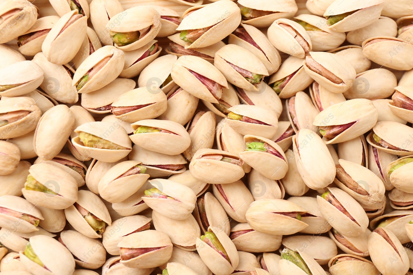 Photo of Tasty unpeeled pistachios as background, top view