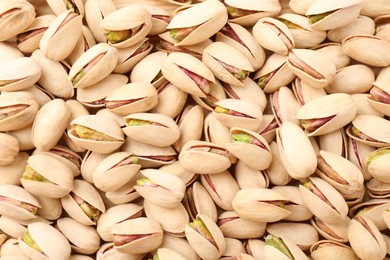 Photo of Tasty unpeeled pistachios as background, top view