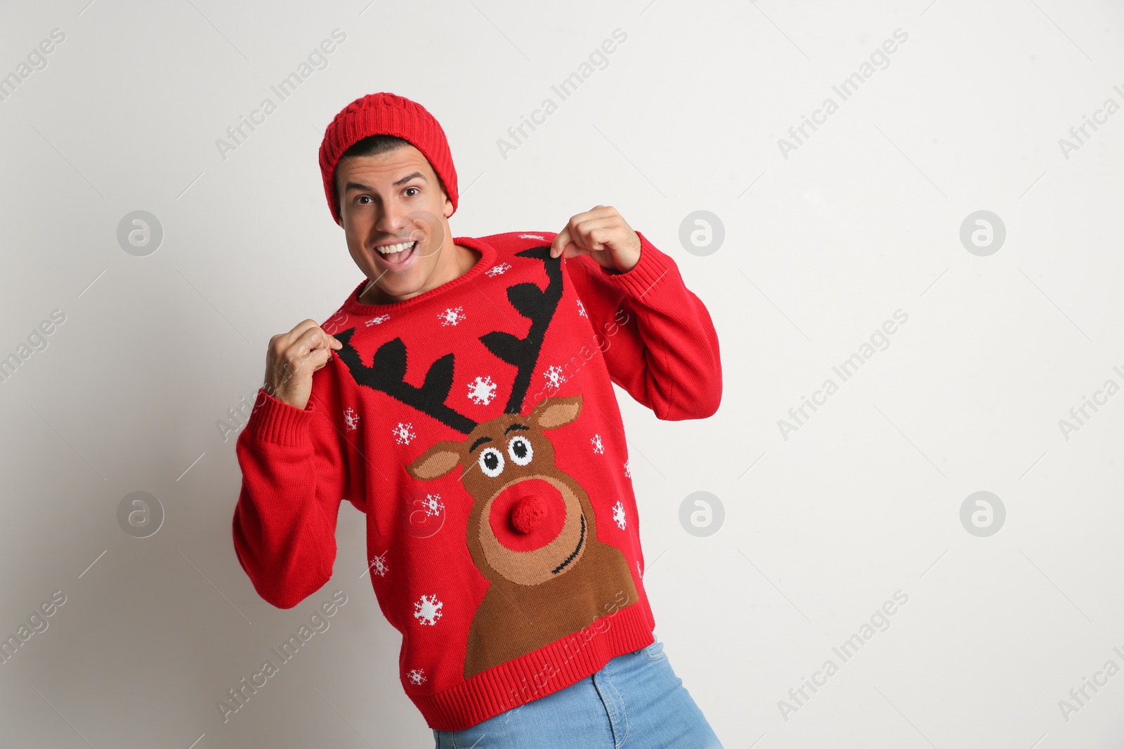 Photo of Happy man in hat showing his Christmas sweater on white background, space for text