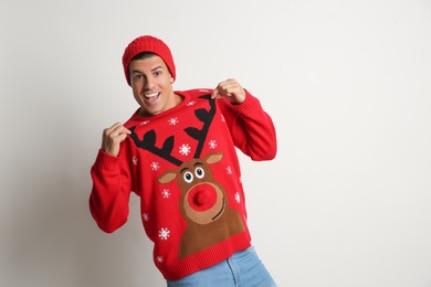Photo of Happy man in hat showing his Christmas sweater on white background, space for text