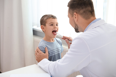 Photo of Children's doctor examining little patient's throat in clinic