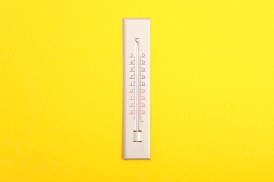 Weather thermometer hanging on bright yellow wall