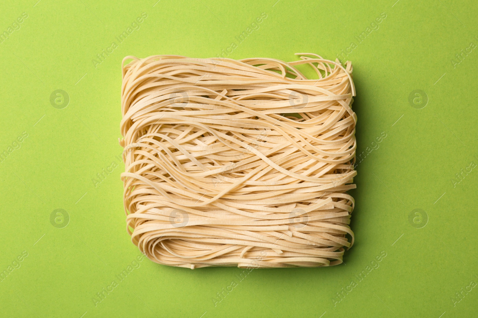 Photo of Block of quick cooking noodles on color background, top view