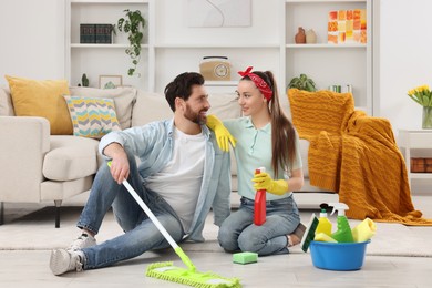 Spring cleaning. Couple with detergents and mop in living room