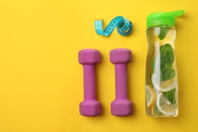 Photo of Bottle with detox drink, measuring tape and dumbbells on color background, top view. Healthy diet