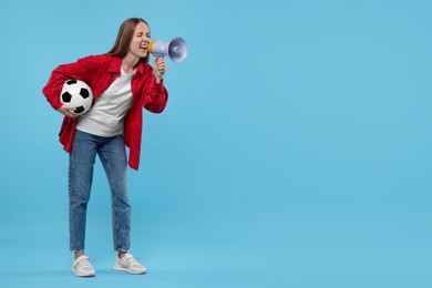 Photo of Emotional sports fan with ball and megaphone on light blue background. Space for text