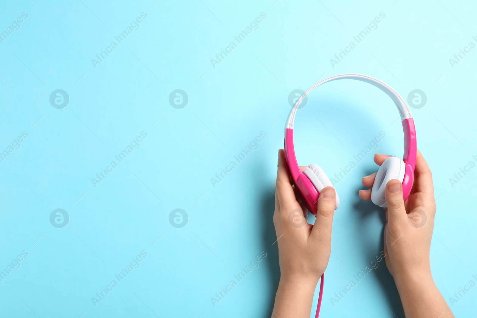 Photo of Woman holding stylish headphones on color background, closeup. Space for text