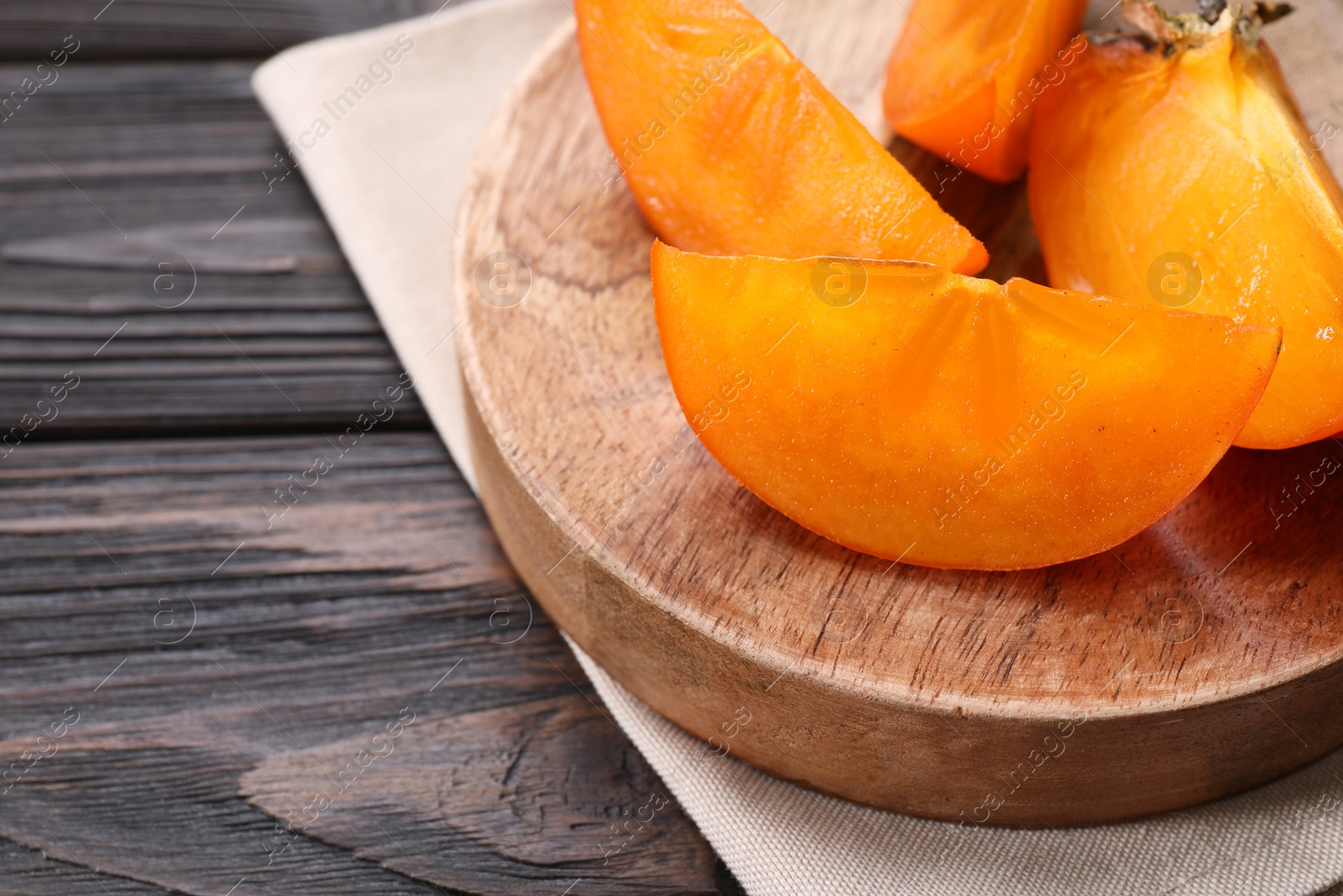 Photo of Pieces of delicious persimmons on wooden table, closeup. Space for text