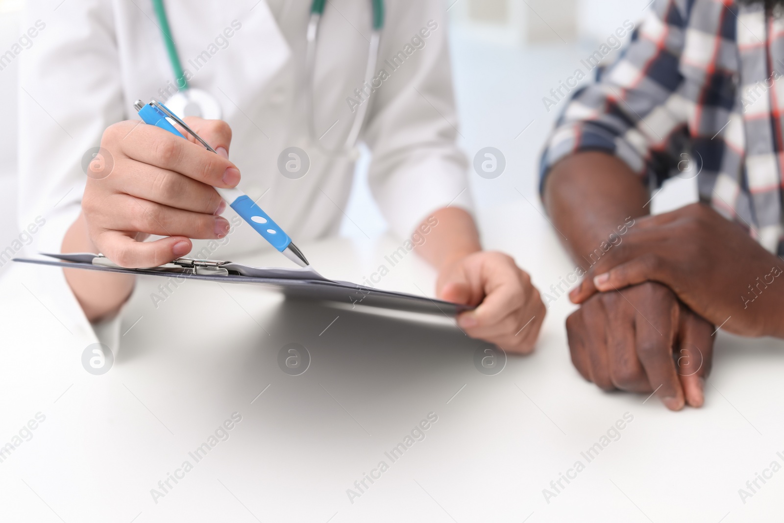 Photo of Young doctor consulting African-American patient in hospital